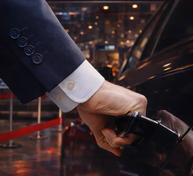 Professional chauffeur service assisting at vehicle for airport dropoff.